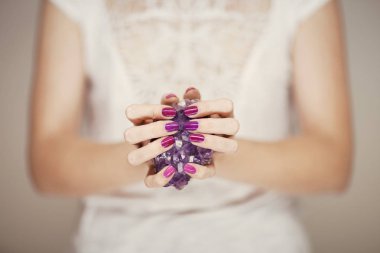 Güzel kadın eller mükemmel pembe tırnak cilası mor Ametist kristal, holding ile arka plan olarak kullanılabilir