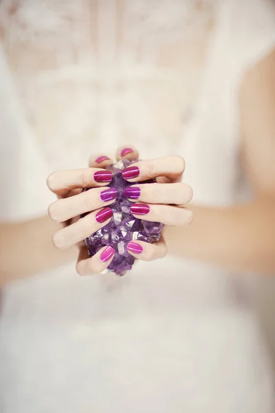 紫のアメジスト結晶を保持している完璧なピンクのマニキュアと美しい女性の手をバック グラウンドとして使用できます — ストック写真