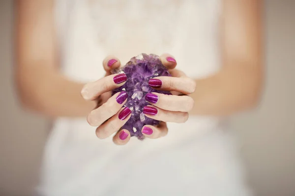 紫のアメジスト結晶を保持している完璧なピンクのマニキュアと美しい女性の手をバック グラウンドとして使用できます — ストック写真