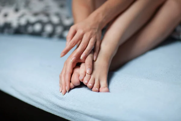 Frau Die Auf Dem Bett Sitzt Und Ihre Füße Hält — Stockfoto