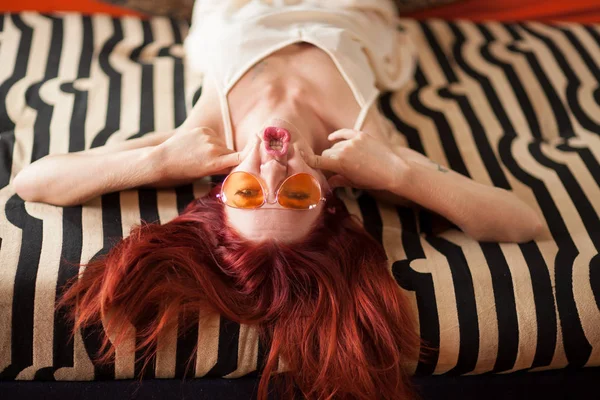 赤い髪とサングラスかなり若い女性がリラックスしたあるし ソファに笑い 感情概念を撮影 — ストック写真
