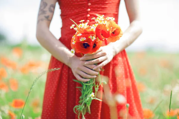 穿着红色连衣裙的美女站在罂粟地里捧着鲜花 用罂粟紧紧地握住她的手 可以作为背景 — 图库照片