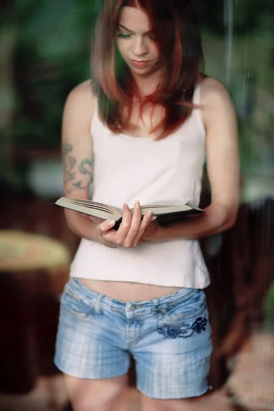 Νεαρή Γυναίκα Διαβάζοντας Ένα Βιβλίο Στο Σπίτι Μπροστά Από Ένα — Φωτογραφία Αρχείου