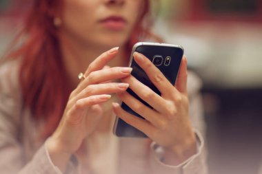 Genç güzel kadın bir sokak kafe, cep telefonu, kapışma kentsel mood holding eller cep telefonu ile yakın meşgul