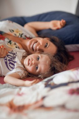 güzel anne kıkırdayarak ve gülüyor ve öpüşme, güzel bir mutlu aile sahne kızıyla yatakta, kucaklamaları 