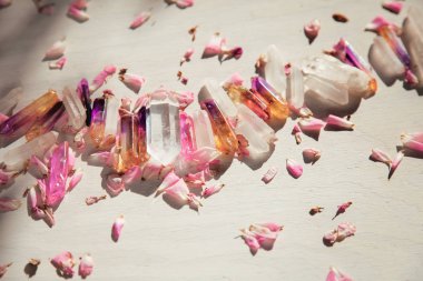 Colorful quartz crystals with pink rose leaves on wooden structure, flat lay background  clipart