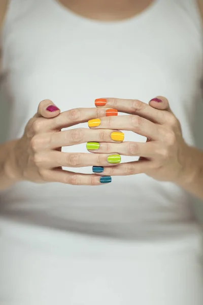Beautiful woman hands with colorful rainbow nail polish, can be used as background