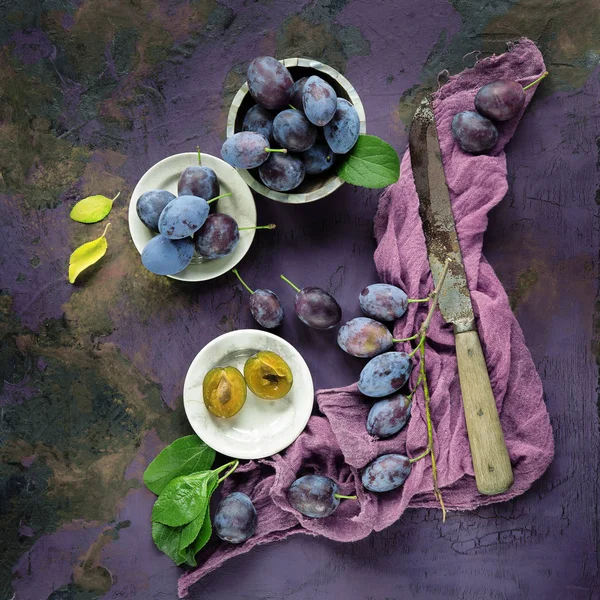 葉とナイフ 素朴な料理写真とバイオレットの紫色の背景に装飾された庭から支店に新鮮でおいしい梅 — ストック写真