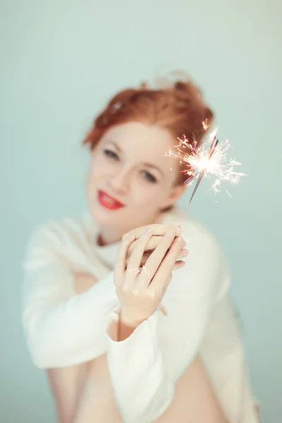美丽的女人用红色的头发持有烟火灯 明亮的冬季毛衣 可以用作背景 — 图库照片