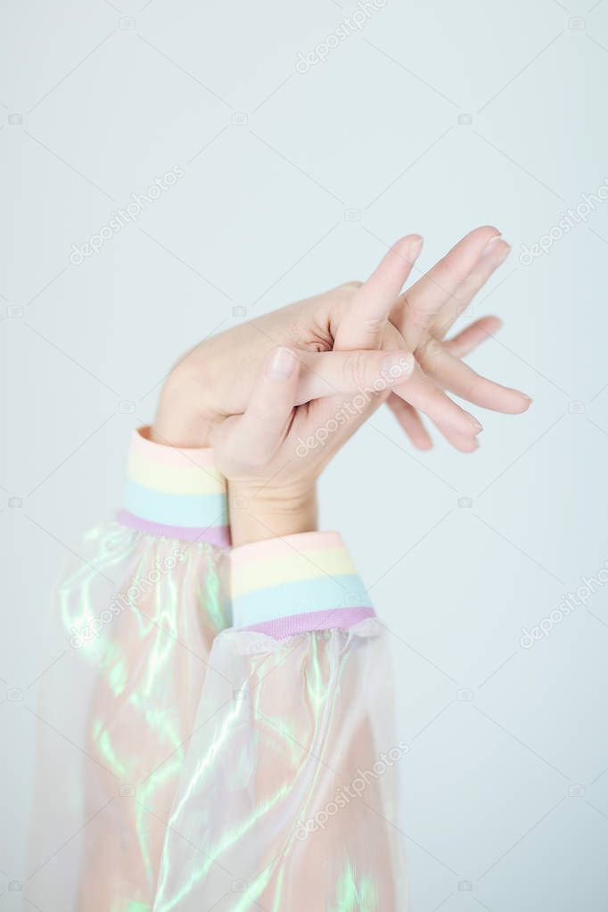 Beautiful woman hands and arms wearing a sweater with holographic effect, modern avantgarde artificial plastic look, perfect fingernails with french manicure