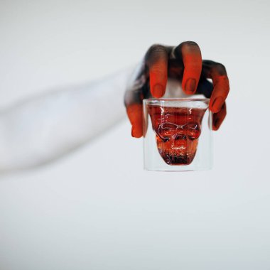Korkunç Halloween canavar el ile kafatası ile bardak kan beyaz arka plan önünde tutan kadar beyaz, kırmızı ve siyah yapmak