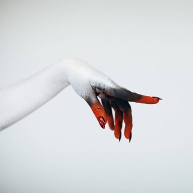 Korkunç Halloween canavar cadı el Beyaz, kırmızı ve siyah makyaj ve beyaz arka plan önünde uzun tüyler ürpertici tırnakları ile 