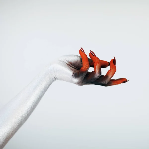 Creepy Halloween monster witch hand with white, red and black make up and long creepy fingernails in front of white background