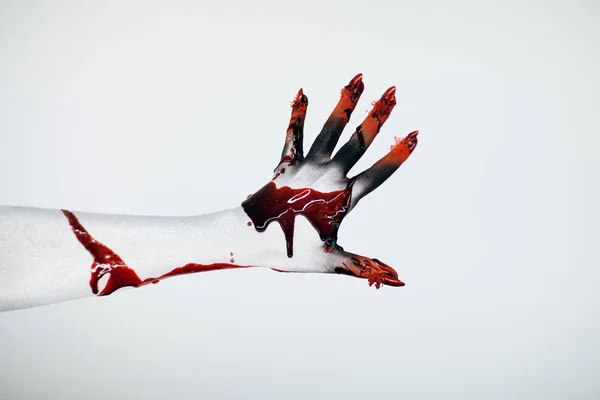 Creepy bloody horror Halloween monster witch hand with white, red and black make up and long creepy fingernails in front of white background