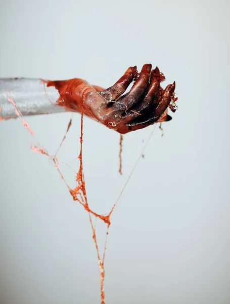 Creepy bloody horror Halloween monster witch hand with white, red and black make up and long creepy fingernails in front of white background