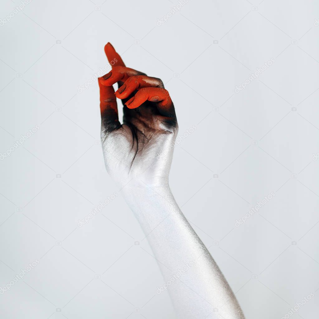 Creepy Halloween monster hand with white, red and black make up in front of white background