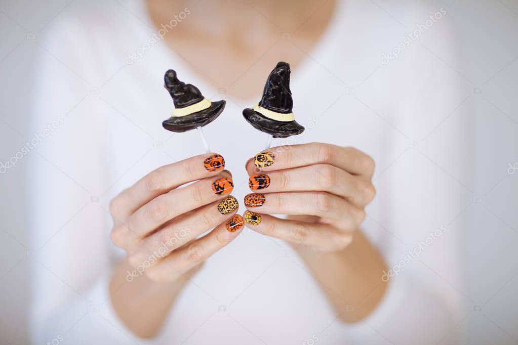 Beautiful woman hands with cute halloween nail polish holding halloween candy can be used as background