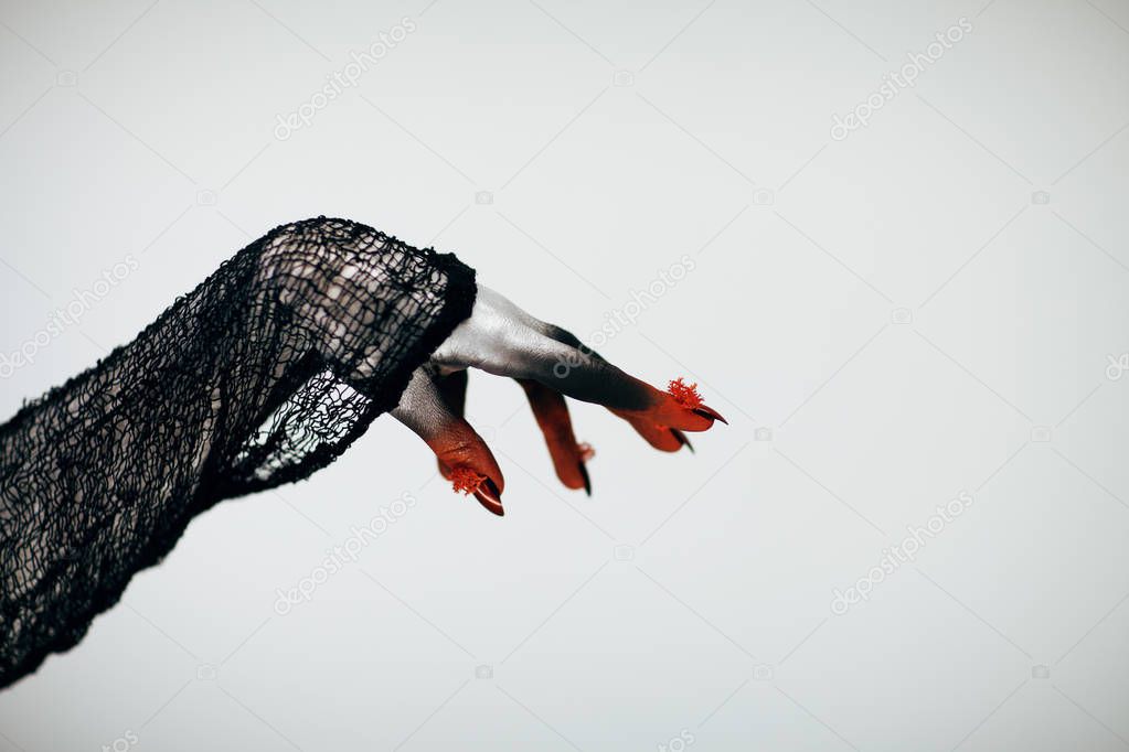 Creepy Halloween monster witch hand with white, red and black make up and long creepy fingernails in front of white background