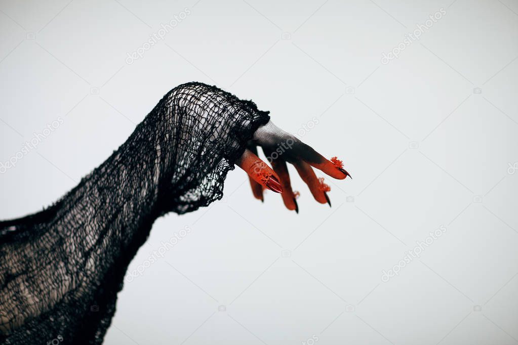 Creepy Halloween monster witch hand with white, red and black make up and long creepy fingernails in front of white background
