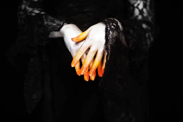 Creepy halloween vampire hands close up in red orange and silver on black, can be used as background