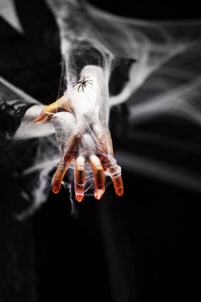 Creepy halloween hand in green and white with spider web, zombie hand on black background