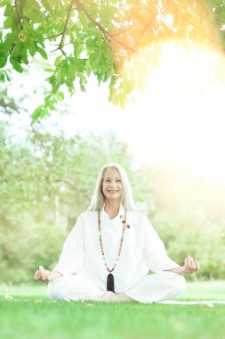 Güzel, en iyi yaş, uzun gri saçlı, dışarıda yoga egzersizi yapan son sınıf öğrencisi kadın.