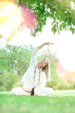 Güzel, en iyi yaş, uzun gri saçlı, dışarıda yoga egzersizi yapan son sınıf öğrencisi kadın.