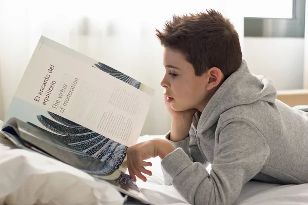 雑誌を読むベッドの子の上に横たわる ロイヤリティフリーのストック写真