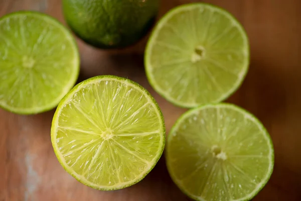 Varios Limones Verdes Juntos Sobre Fondo Madera Limas Cortadas — Foto de Stock