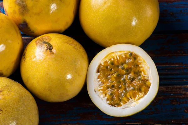 Passion fruit cut in half and some whole passion fruit. Wood background. Top view
