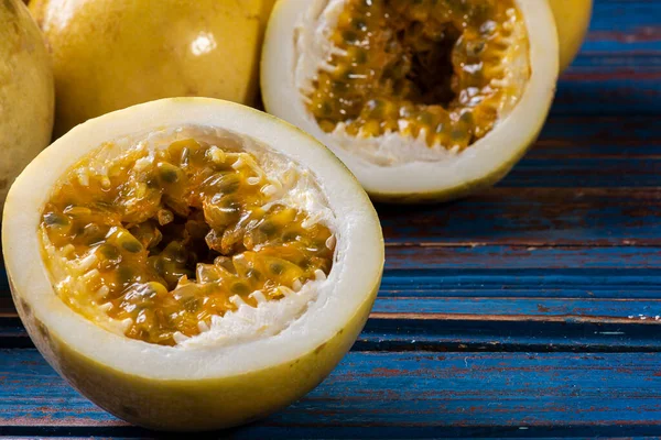 Passion fruit cut in half and some whole passion fruit. Wood background