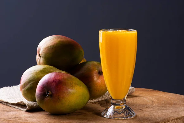 Mango juice. Some mangos together on wooden background