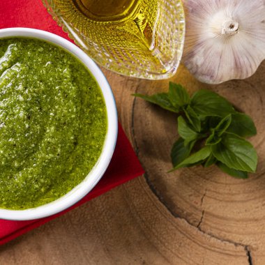 Fonda malzemeler olan bir kasede pesto sosu. Zeytinyağı, sarımsak ve fesleğen..
