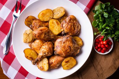 Tavuk parçalanmış, patates ve soğanlı, beyaz bir tabakta.
