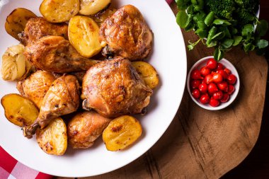 Tavuk parçalanmış, patates ve soğanlı, beyaz bir tabakta.