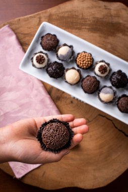 Brigadeiro 'yu tutan bir çocuk eli. Tipik Brezilya tatlısı. Arka planda bir sürü tugay üyesi var.