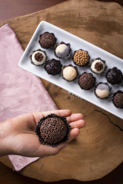 Brigadeiro 'yu tutan bir çocuk eli. Tipik Brezilya tatlısı. Arka planda bir sürü tugay üyesi var.