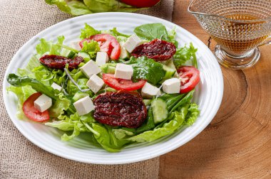 Marul, roka, salatalık, peynir ve kurutulmuş domatesli yeşil salata..