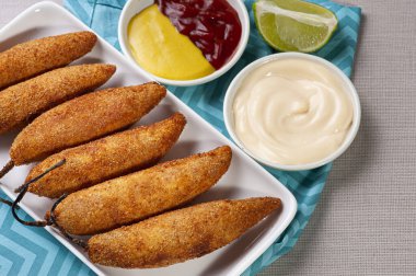 Kızarmış biber, kurutulmuş et ve krem peynirle doldurulmuş. Yanında mayonez, ketçap ve hardal var..