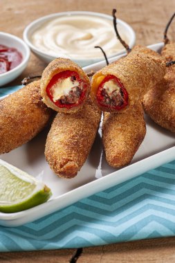 Kızarmış biber, kurutulmuş et ve krem peynirle doldurulmuş. Yanında mayonez, ketçap ve hardal var..