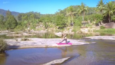 dron yavaş yavaş mat genç kadın kaldırır ve palmiye ağaçları karşı köpüklü rapids banka üzerinde gösterir