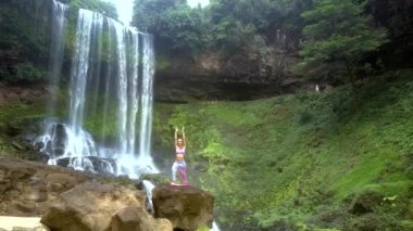 Harika görüntüsü kız eller yukarı pozuyla yoga Milli Parkı içinde yükseklikten düşen su karşı taşa tutar