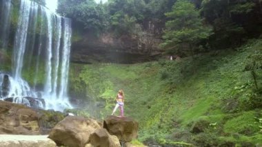 üst panorama genç kadın büyük kaya şelale Doğa Park yakınındaki yoga poz ayarlar