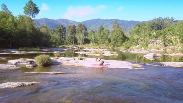 无人机查看运动女孩在石头上做瑜珈在蓝天淌的高山河流 — 图库视频影像