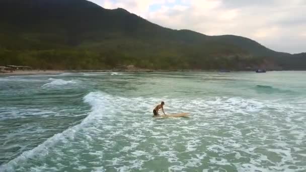 Mädchen hält Surfbrett auf Wasser und überwindet schäumende Wellen — Stockvideo