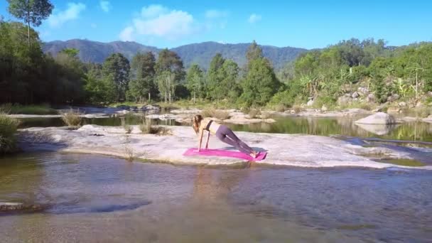 Flycam removes from girl in yoga shows river rapids — Stock Video