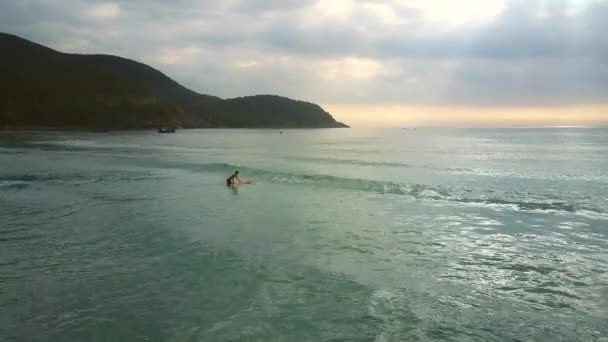 Menina detém prancha de surf tenta sentar e montar em ondas — Vídeo de Stock