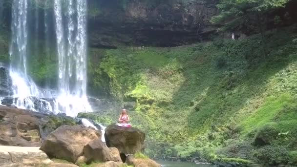 Frau sitzt im Lotus gegen steiles grünes Flussufer — Stockvideo