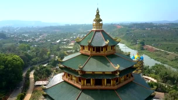 Беспилотник кружит над храмом на верхних этажах зеленых крыш против долины — стоковое видео