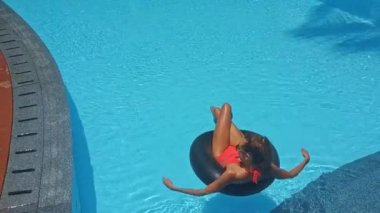 Otelin yakınında yüzme havuzunda şişme halkası üzerinde Orange at kuyruğu ile arka görünümü kız yüzüyor